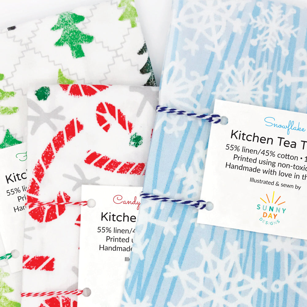 3 holiday kitchen tea towel designs by Sunny Day Designs. Made in the USA. Fun tea towels featuring green Christmas trees, red candy canes, and blue and white snowflakes.