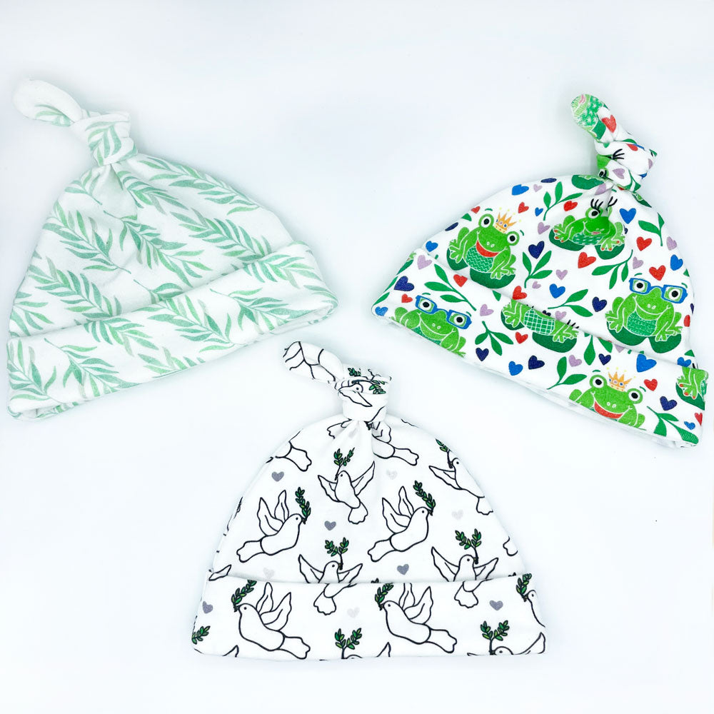 3 organic cotton baby hats by Sunny Day Designs are shown on a white background - printed organic baby hat styles shown are Eucalyptus print, Happy Hoppers frog print, and Lovey Dovey bird print
