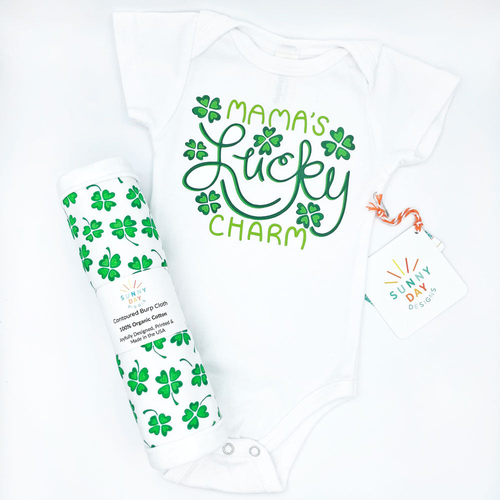 Feeling Lucky four-leaf clover printed organic cotton burp cloth and a white baby onesie printed with a green "Mama's Lucky Charm" print design by Sunny Day Designs. These lucky Irish-themed, organic cotton baby products are perfect for St. Patrick's Day!