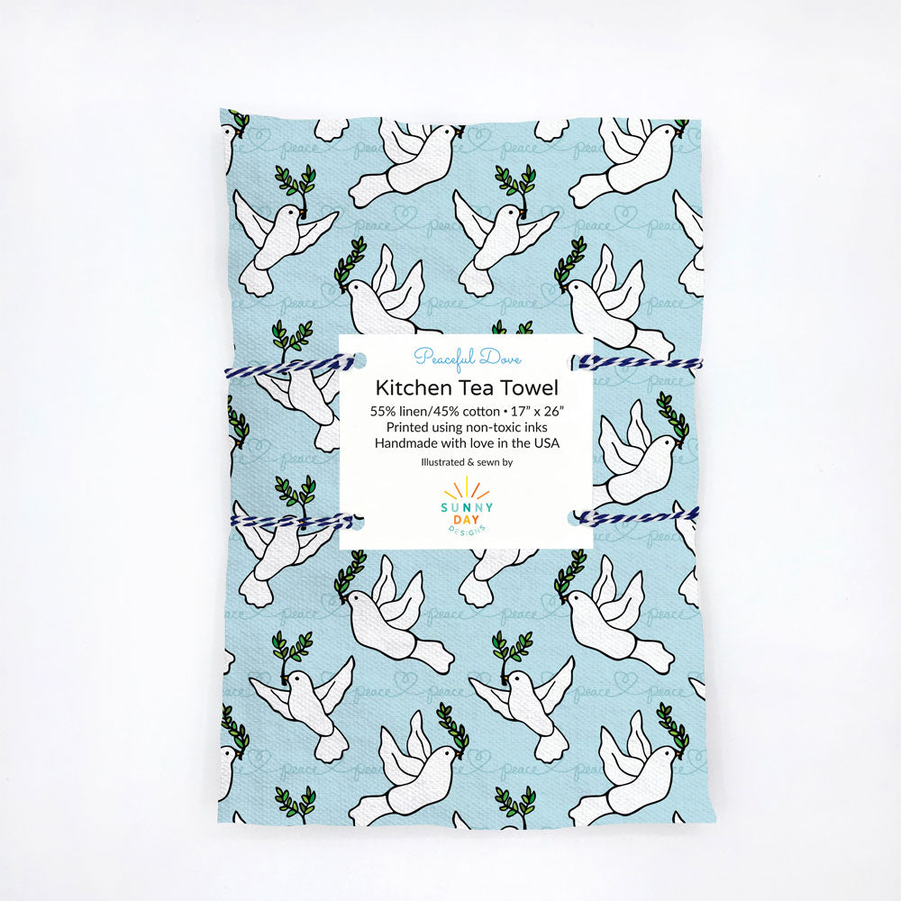 Our Peaceful Dove printed tea towel is shown on a white background - a light Blue printed linen/cotton tea towel with white doves holding green olive branches to symbolize peace