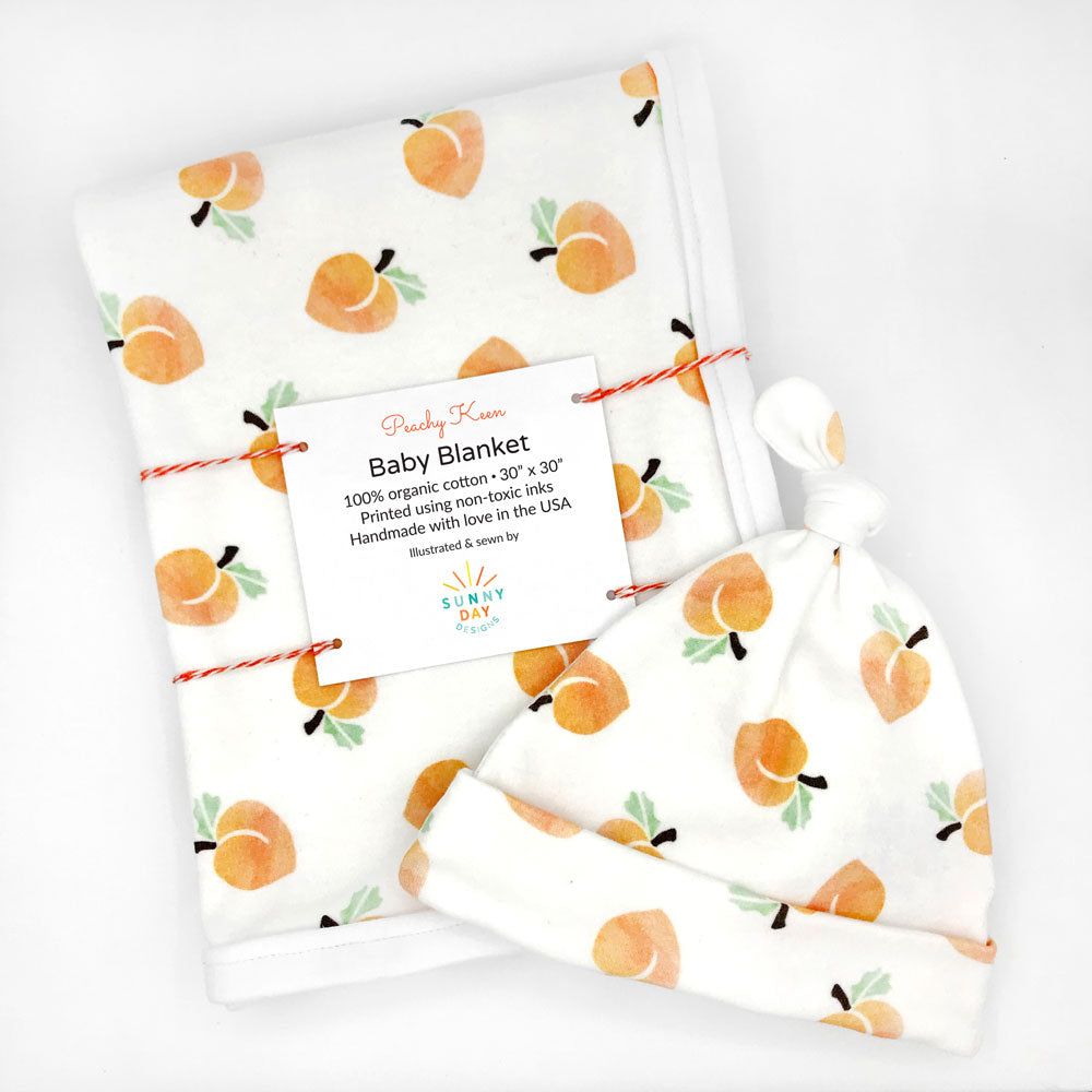 Georgia peachy keen printed organic cotton baby blanket and hat by Sunny Day Designs is packaged and shown on a white background.