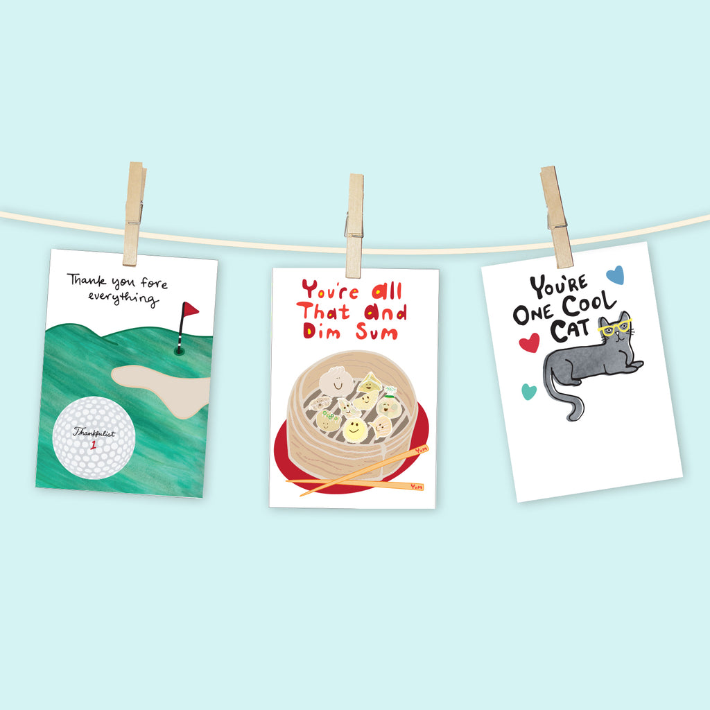 3 colorful greeting cards by Sunny Day Designs are clipped to a line with clotheslines against a light blue background