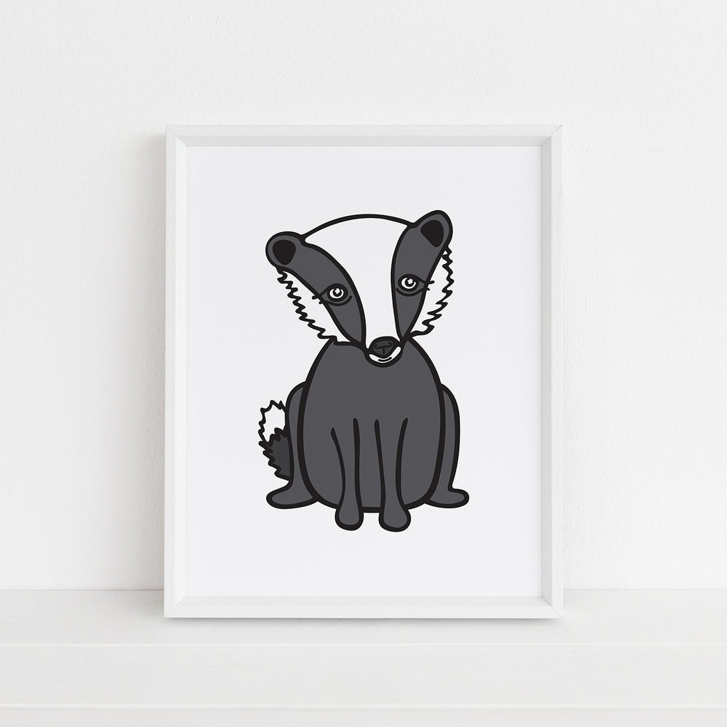 An adorable animal-themed illustrated 8x10 art print of a gray, black, and white badger is shown inside a white picture frame on a white ledge.