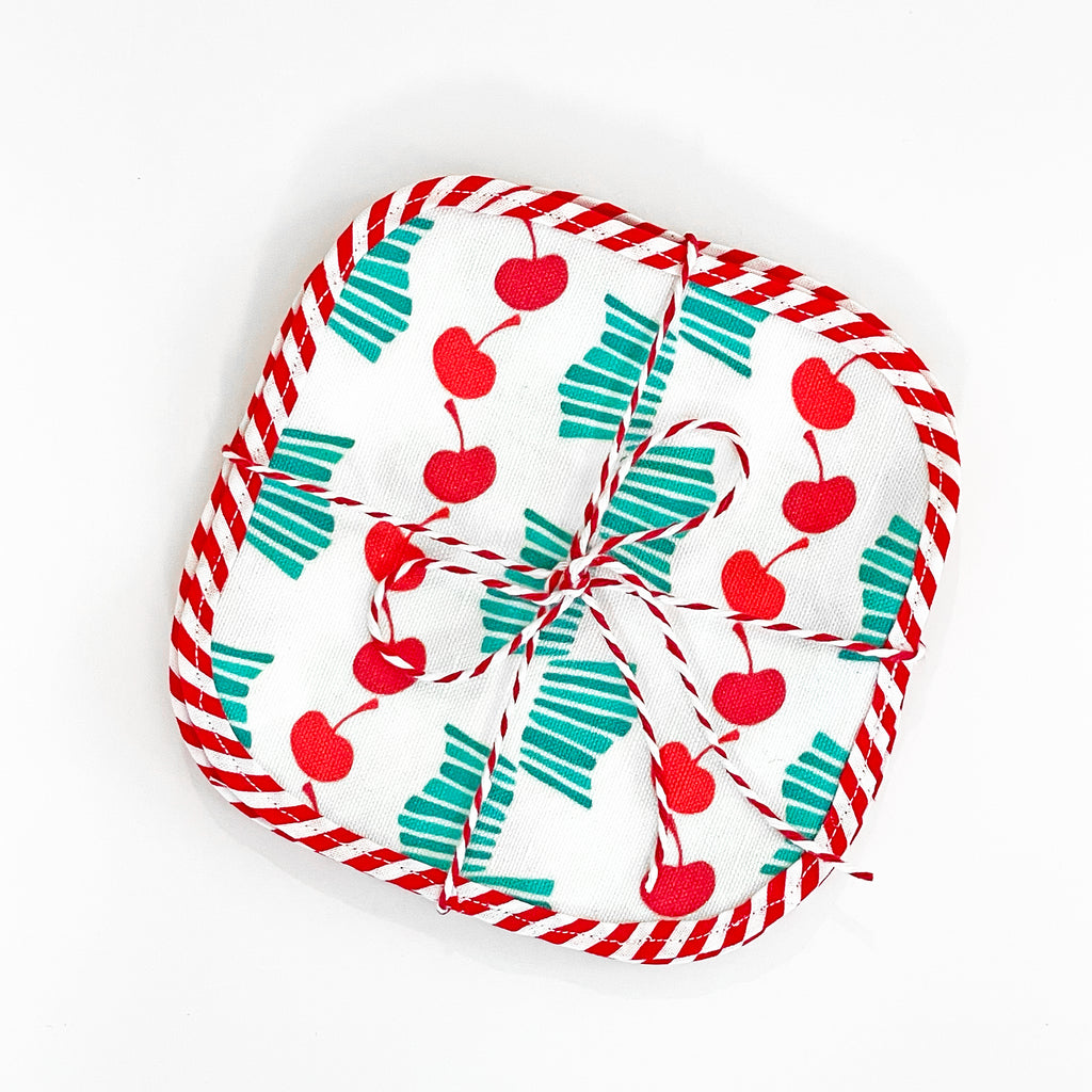 Packaged set of Cheerful Cherries fabric cocktail napkins, neatly tied with red and white striped twine. The napkins feature bright red cherries and turquoise stripes, creating a charming and cheerful design.