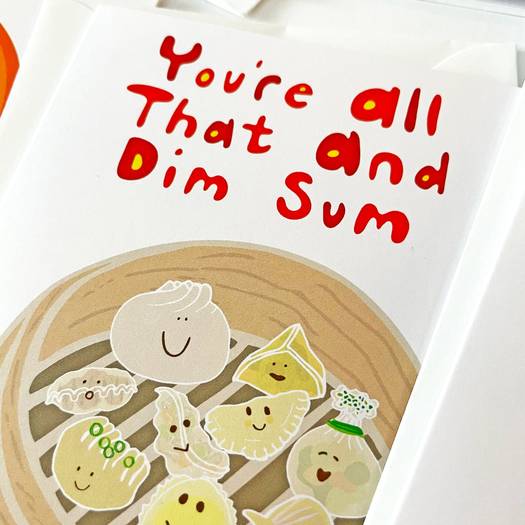 Close-up image of a 'You're All That and Dim Sum' greeting card by Sunny Day Designs, featuring a cute illustration of various dim sum characters with happy faces inside a bamboo steamer basket.
