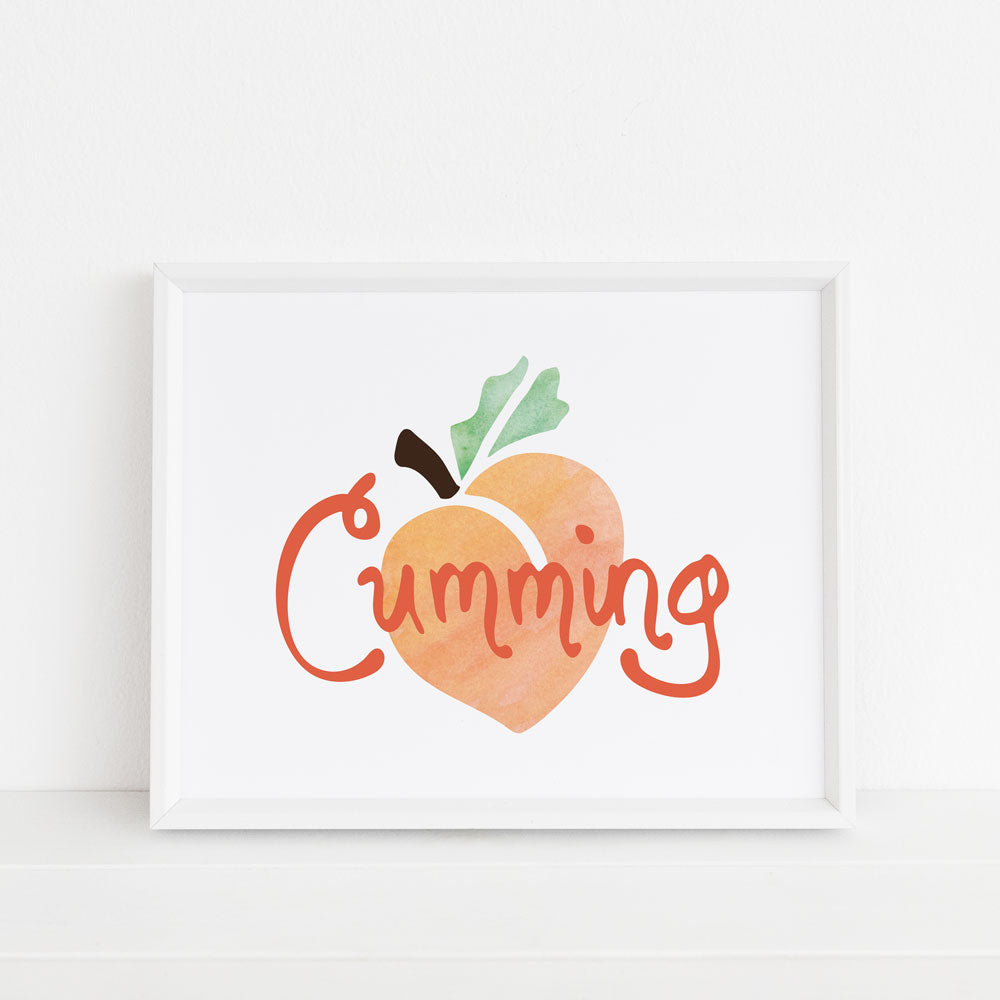 Perfect for residents of Cumming, Georgia, this 8x10 art print features a watercolor peach with hand lettered orange "Cumming" text on top. In the photo, this was art is displayed inside a white frame. Designed by Sunny Day Designs and made in the USA.