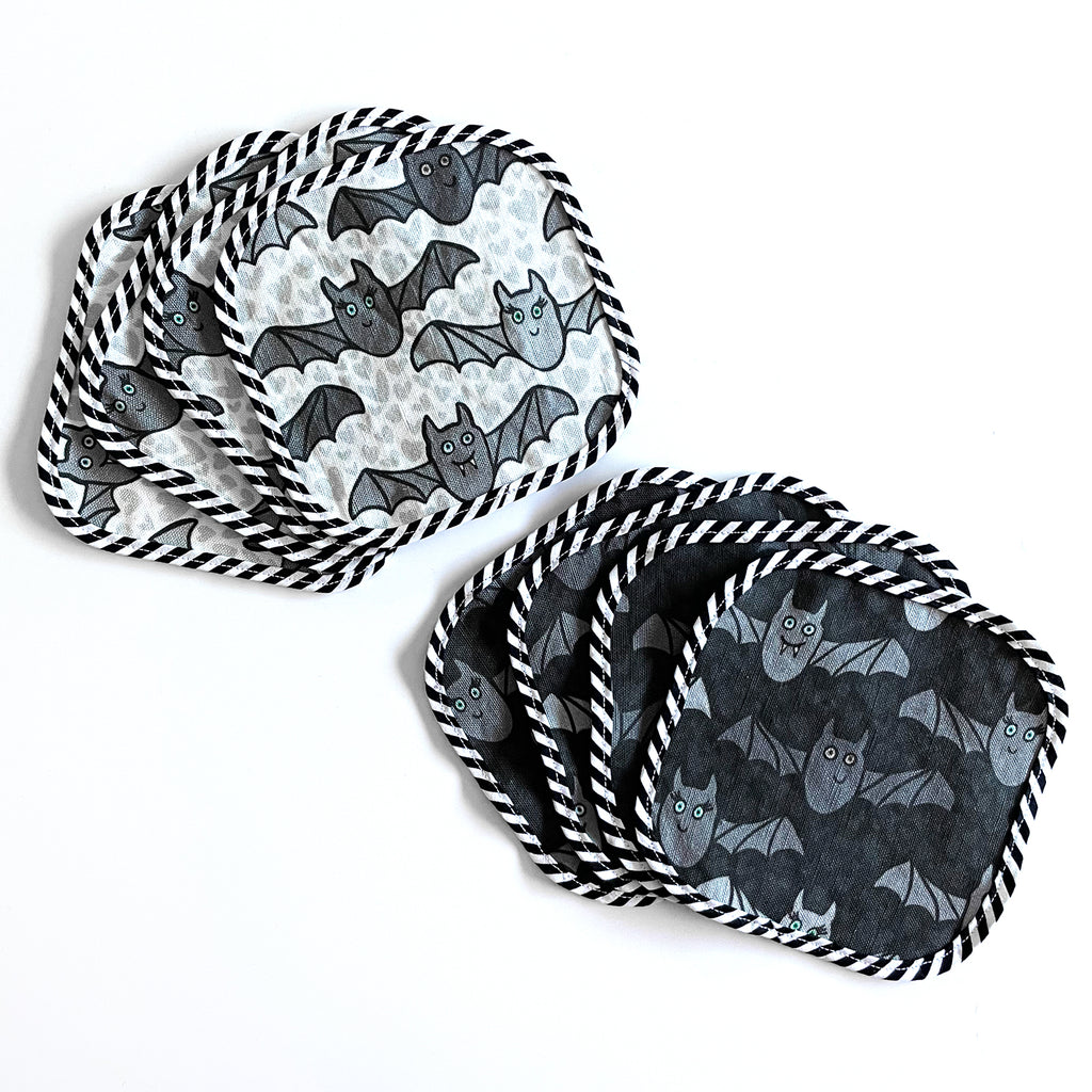 A cute set of 8 reusable square cocktail napkins by Sunny Day Designs is shown in a Halloween themed Benevolent Bats print design and features 4 handmade cocktail napkins in a dark gray color and 4 linen/cotton cocktail napkins in a light gray colored print. This set of 8 reusable party napkins is made in the USA.