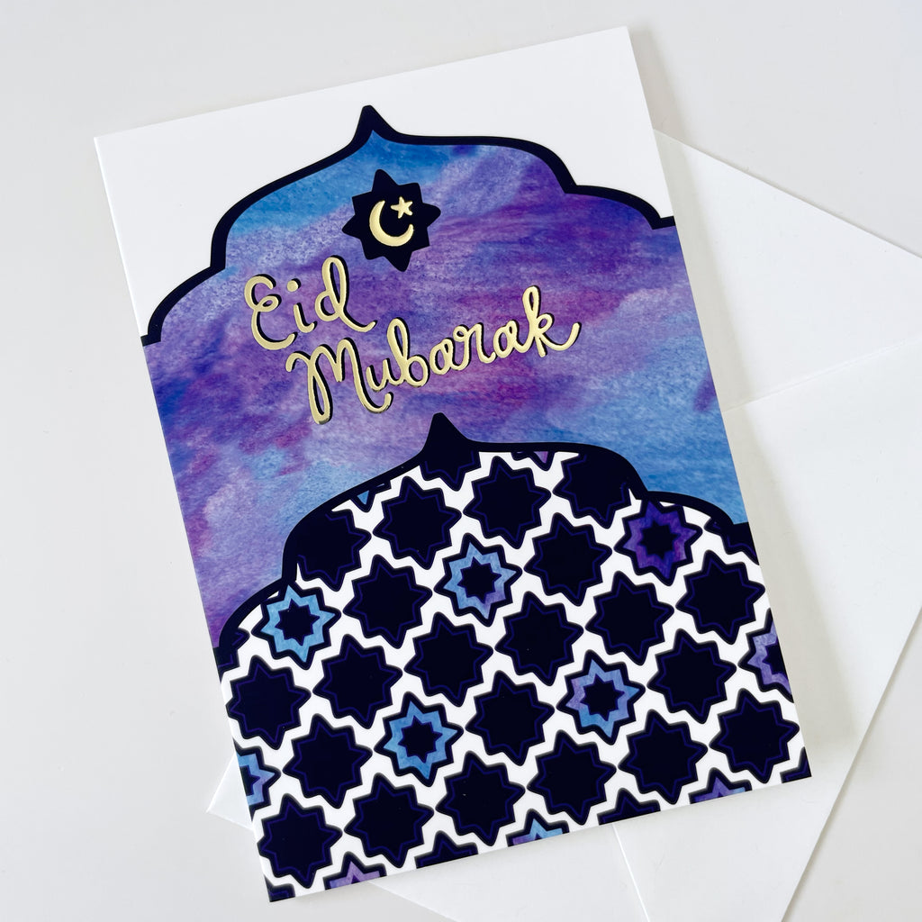 A colorful blue and purple watercolor Eid al-Fitr greeting card with metallic gold embossed "Eid Mubarak" text on cover is shown on a white background with 1 white envelope. This beautiful made in the USA Islamic greeting card is the perfect way to celebrate the end of Ramadan and send Eid greetings to Muslim friends, family & more.