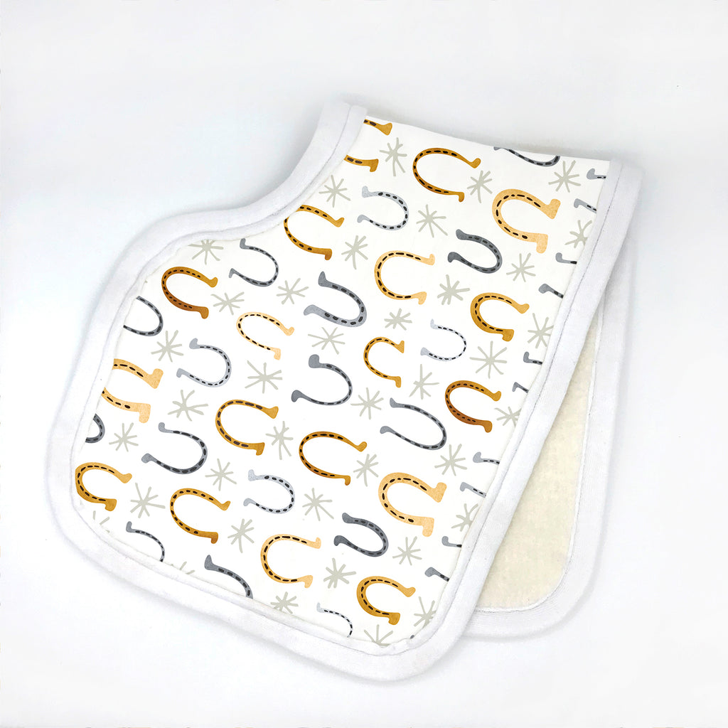 an equestrian themed horseshoe printed contoured burp cloth in shades of gray and gold is folded in half on a white background.