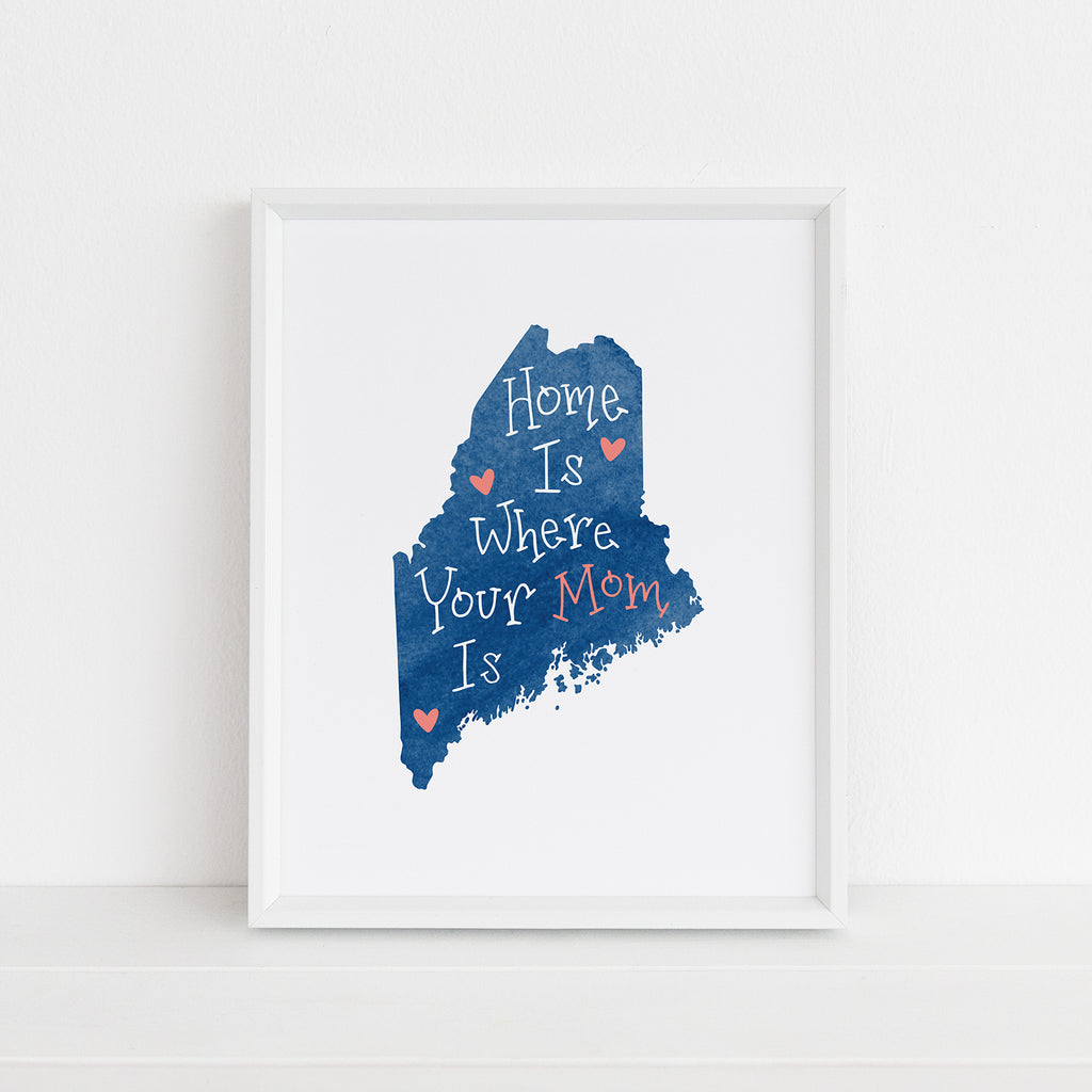 A framed 8x10 piece of wall artwork is shown that makes a sweet and sentimental gift for mom, a blue watercolor map of Maine with white and coral text that reads: 'Home Is Where Your Mom Is' on a white background 