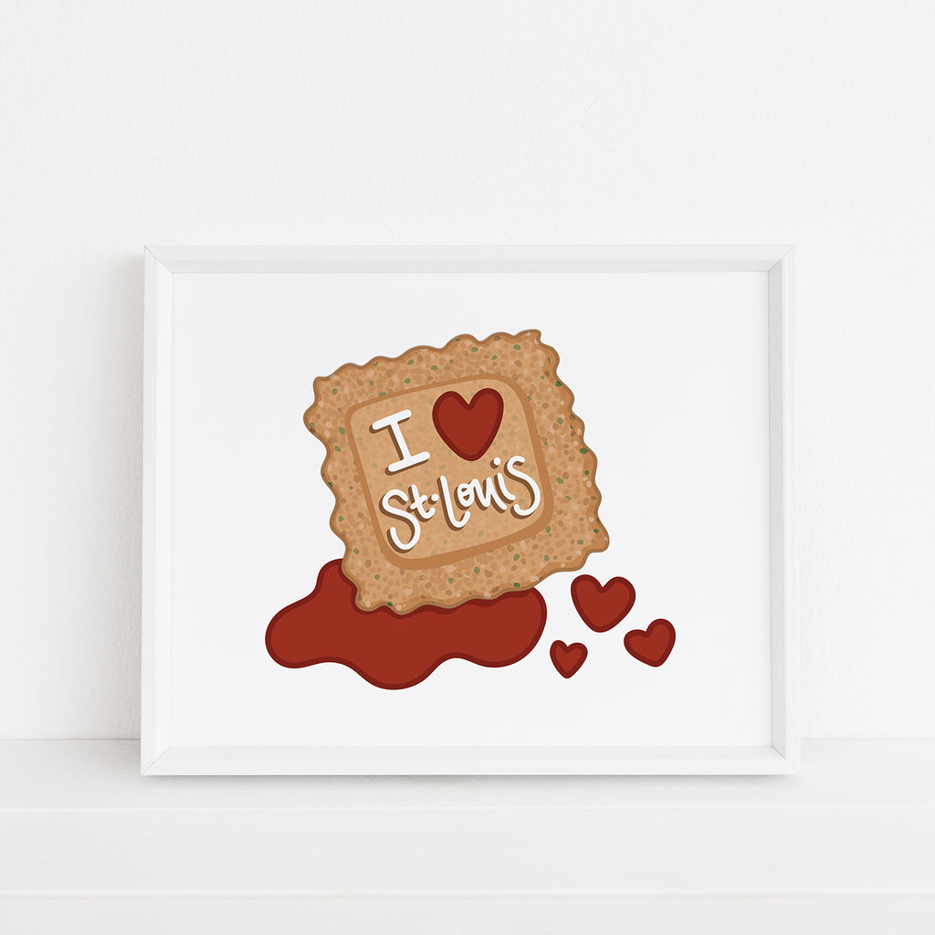 A St. Louis food themed 8x10 wall art print featuring an iconic food from St. Louis: a toasted ravioli with marinara sauce is shown on a white background with 3 marinara sauce hearts and the words "I Heart St. Louis" in hand lettered text on top of the ravioli. This STL foodie inspired giclee art print is shown framed inside a white picture frame.