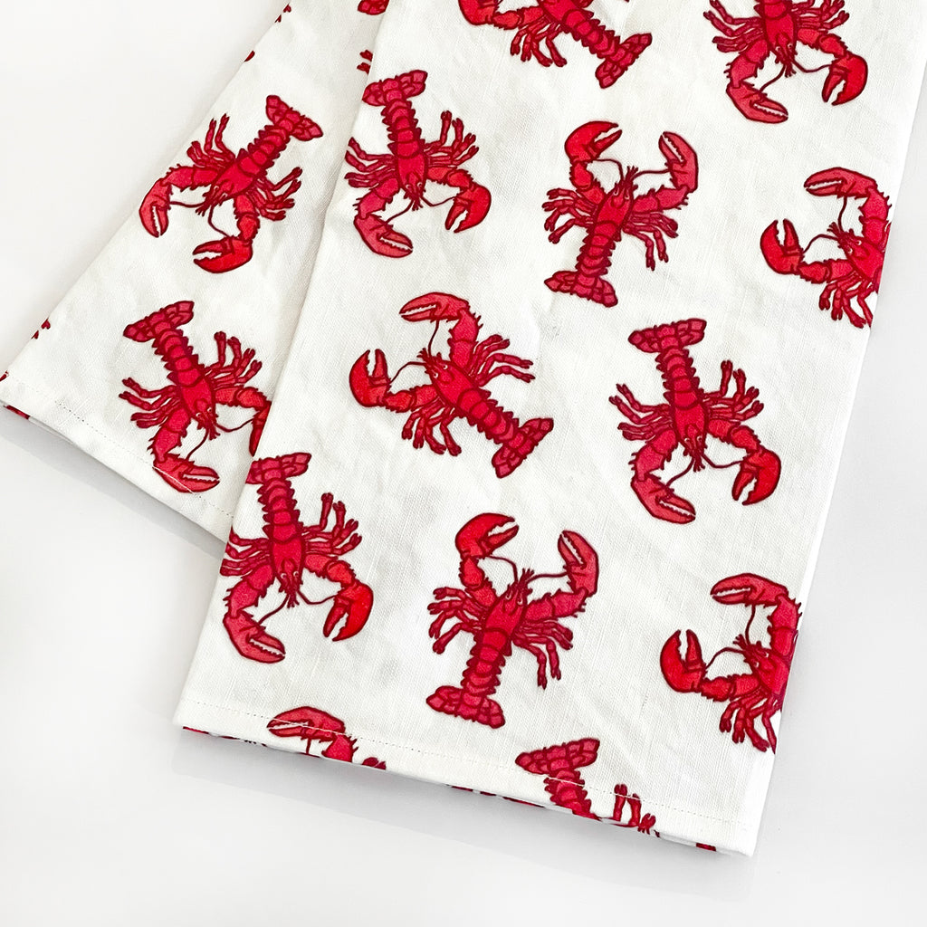 Angled close-up of the Lobster Tea Towel showing detailed red lobster prints on a clean white background. The towel’s durable fabric makes it both decorative and functional for everyday kitchen use.