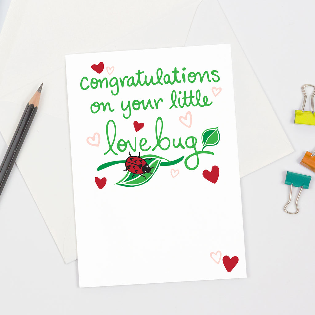 A sustainably sourced, made in the USA greeting card that is perfect way to say congratulations when someone has a baby - this card has a red, green, black, and pink ladybug/nature themed cover design with text that says "Congratulations on your little lovebug"