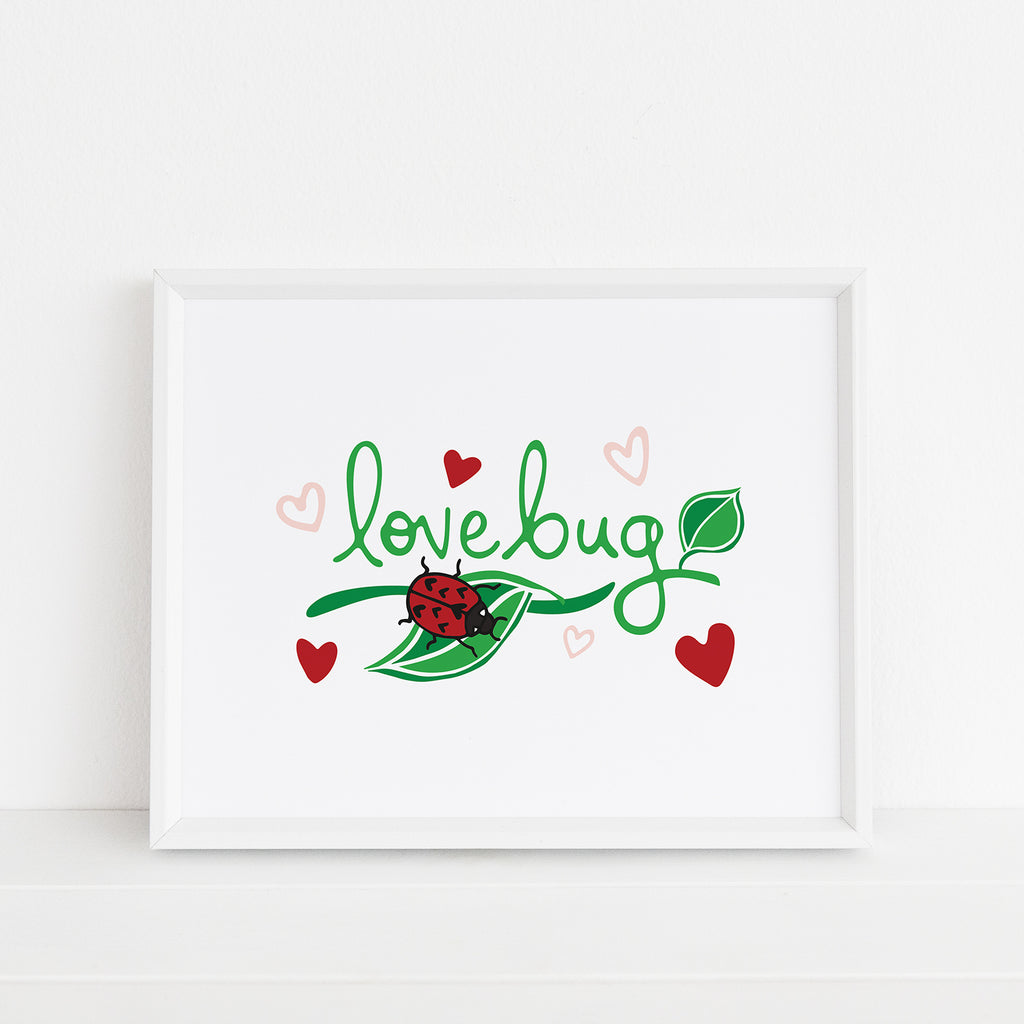 A nature-inspired art print featuring a red ladybug with heart-shaped black spots lounging on a green leaf with the word "lovebug" written above in green hand lettered text. This adorable cute bug print also includes pink and red heart accents