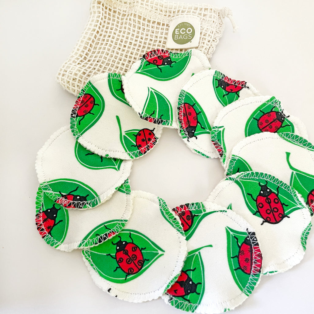Eco-friendly reusable facial rounds with a ladybug design fanned out in a circle, with an organic cotton wash bag in the background.