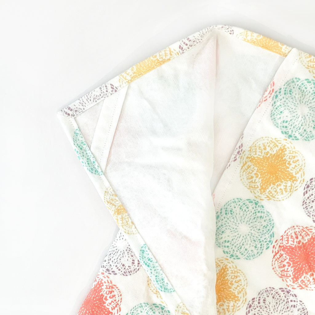 Detailed view of the Modern Mandala Tea Towel's hanging corner loop feature. The towel’s bright circular mandala pattern in various colors on a white fabric combines style with functionality, making it easy to hang and store.