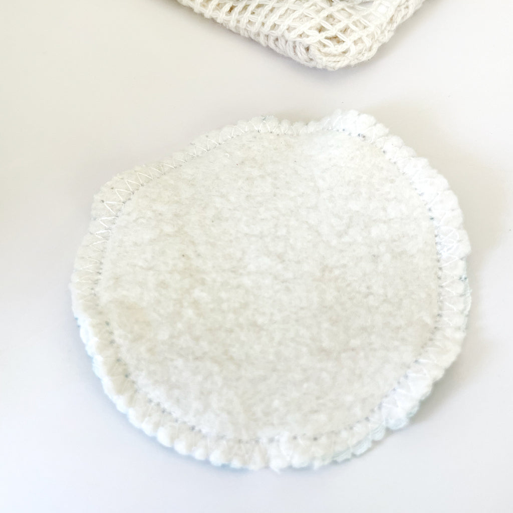 A photo showing the reverse side of a circular organic cotton reusable facial wipe, which shows the fuzzy and soft natural-colored organic cotton fleece fabric. This small handmade washable face wipes by Sunny Day Designs are perfect for removing makeup from sensitive skin!