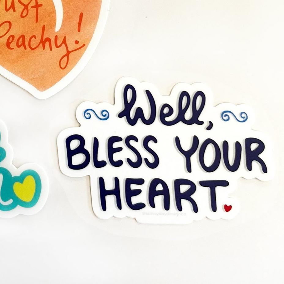 Set of three vinyl stickers from Sunny Day Designs featuring Southern sayings: 'Just Peachy!' in orange, 'Southern Charmer' in turquoise with a yellow heart, and 'Well, Bless Your Heart' in bold navy blue with a red heart and blue swirls, each with a white outline background.