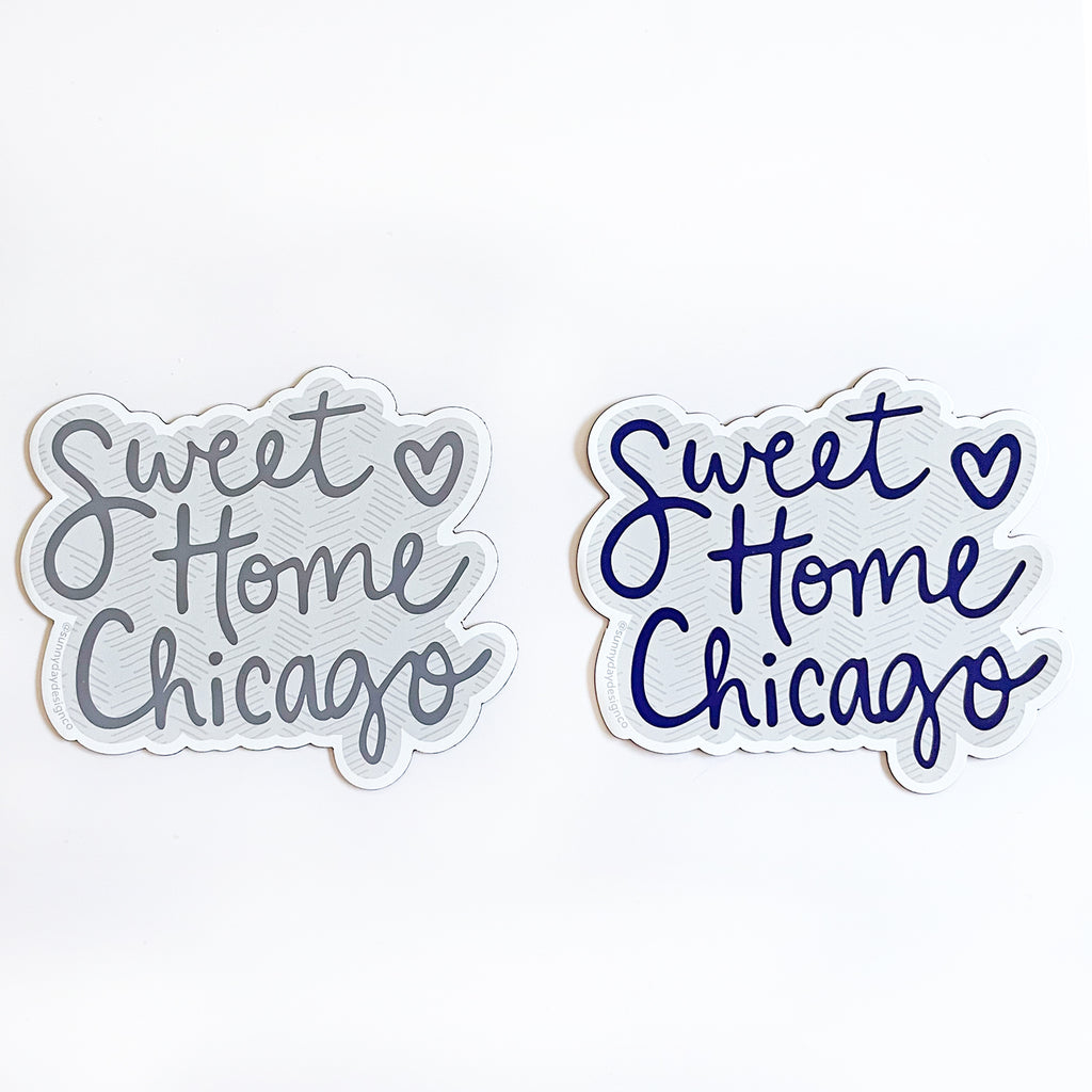 2 different color options of these fun "Sweet Home Chicago" song-themed vinyl magnets are pictured side-by-side on a white background. At left, a gray version of the Chicago magnet is shown with charcoal hand lettered text and a light gray patterned background; At right, a navy blue version of the Chicago magnet is shown with navy blue hand lettered text and a light gray patterned background. Both thin vinyl magnets are made in the USA and were designed by Sunny Day Designs in Madison, WI.