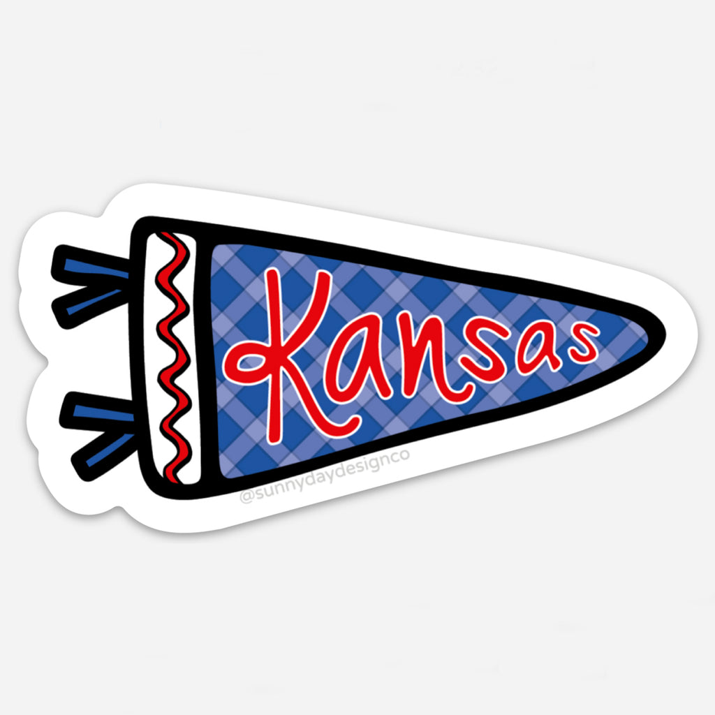 Vinyl magnet in the shape of a pennant flag with a blue plaid background and the word “Kansas” in bold red script. Embellished with red and blue tassels and a thick black outline, designed by Sunny Day Designs to celebrate University of Kansas spirit.