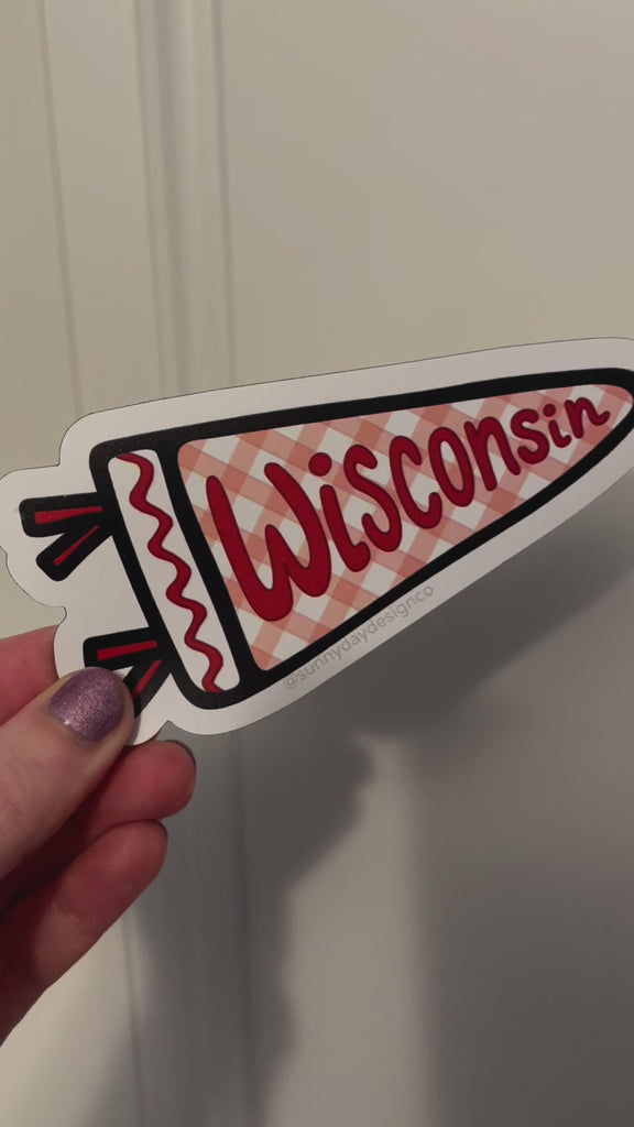 A video showing details of the red, white and black "Wisconsin Pennant" vinyl magnet by Sunny Day Designs being attached to a metal door. This high quality vinyl magnet is designed in Madison, Wisconsin and made in the USA. It would be a great graduation gift, student gift, souvenir of Madison, WI, or a great small gift for any Wisconsin sports fan! 