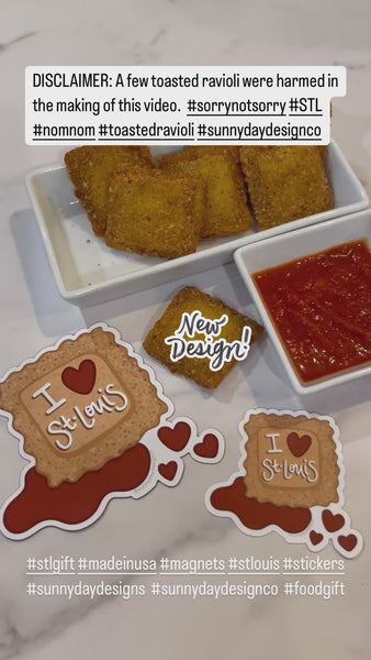 A video showing a plate of toasted ravioli and red marinara dipping sauce (a local food specialty of St. Louis, MO) is shown on a marble countertop alongside a St. Louis-themed toasted ravioli magnet and sticker by Sunny Day Designs. In the video, a hand reaches out to grab a toasted ravioli, dip it in marinara sauce, then a person off-camera takes a bite. Meanwhile, the text "New Design!" appears to highlight that these fun St. Louis souvenir stickers and magnets are a new product recently released.