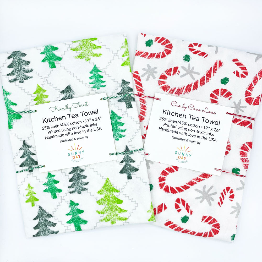 This fun set of 2 Christmas tea towel is packaged with green and red baker's twine and designed and made in the USA by Sunny Day Designs. 1 Friendly Forest woodland Christmas tree kitchen towel and 1 candy cane lane dish towel made from linen/cotton fabrics.