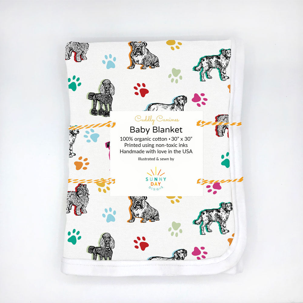 Cuddly Canines dog-themed printed baby blanket by Sunny Day Designs is folded, packaged, and shown against a white background. Made in the USA from Organic cotton fabric.