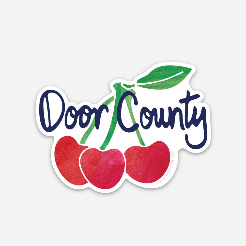 Door County, Wisconsin Cherry themed vinyl sticker by Sunny Day Designs features red and green watercolor cherries on a white background with navy blue handwritten text that says "Door County". This souvenir sticker is made in the USA and designed by Sunny Day Designs in Madison, WI.