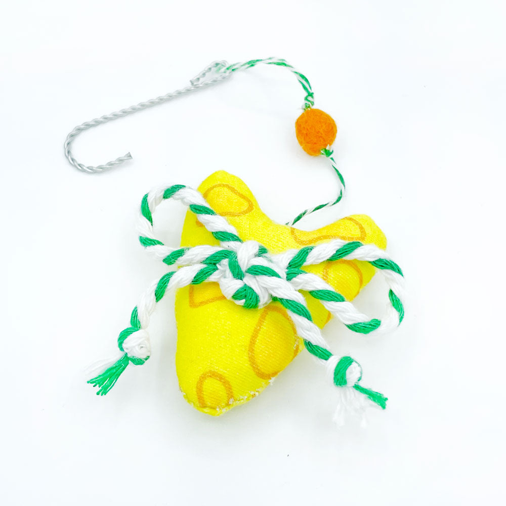 The Cheese Heart Christmas Ornament by Sunny Day Designs is shown laying flat on a white background. Each ornament is made from our yellow Cheesy printed organic cotton fabric and embellished with a green/white Baker's Twine bow and a mustard yellow wool pom pom. Handmade in the USA by Sunny Day Designs in Madison, Wisconsin. Makes a great gift for any Green Bay Packers fan!