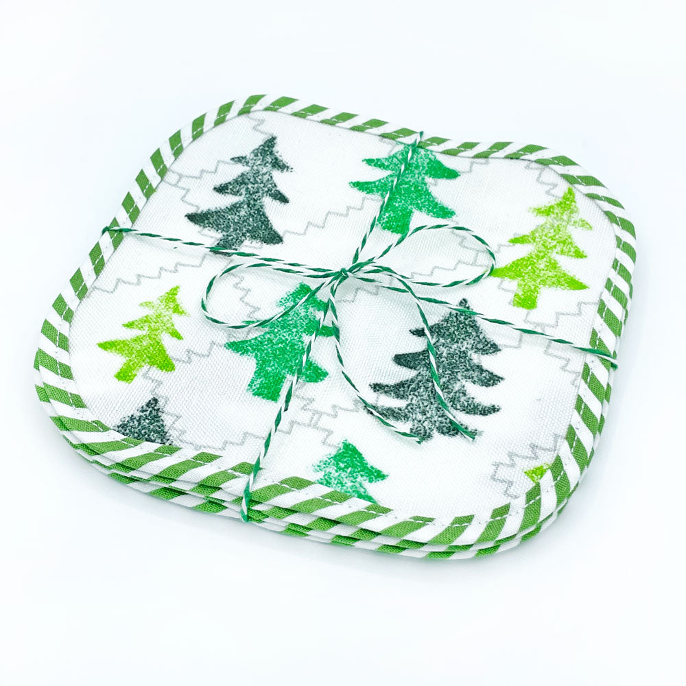 A set of 4, packaged, green Friendly Forest woodland tree Reusable Fabric Cocktail Napkins by Sunny Day Designs. Made in the USA of linen/cotton fabric with green/white striped binding around each square. Packaged with baker's twine on a white background.