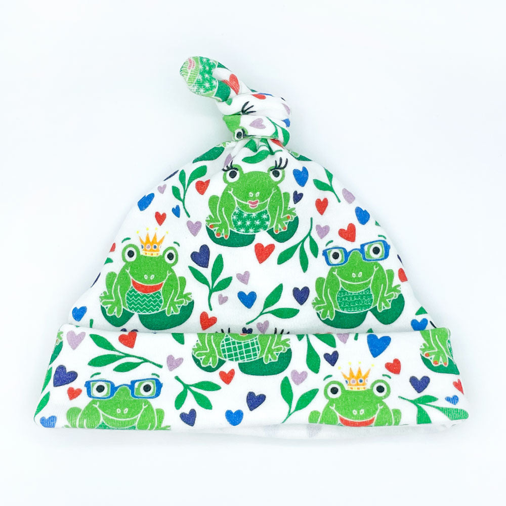 Colorful, green frog-themed, organic cotton newborn baby hat featuring our cheerful "Happy Hoppers" frog-themed print design by Sunny Day Designs Tie top baby hat shown on a white background