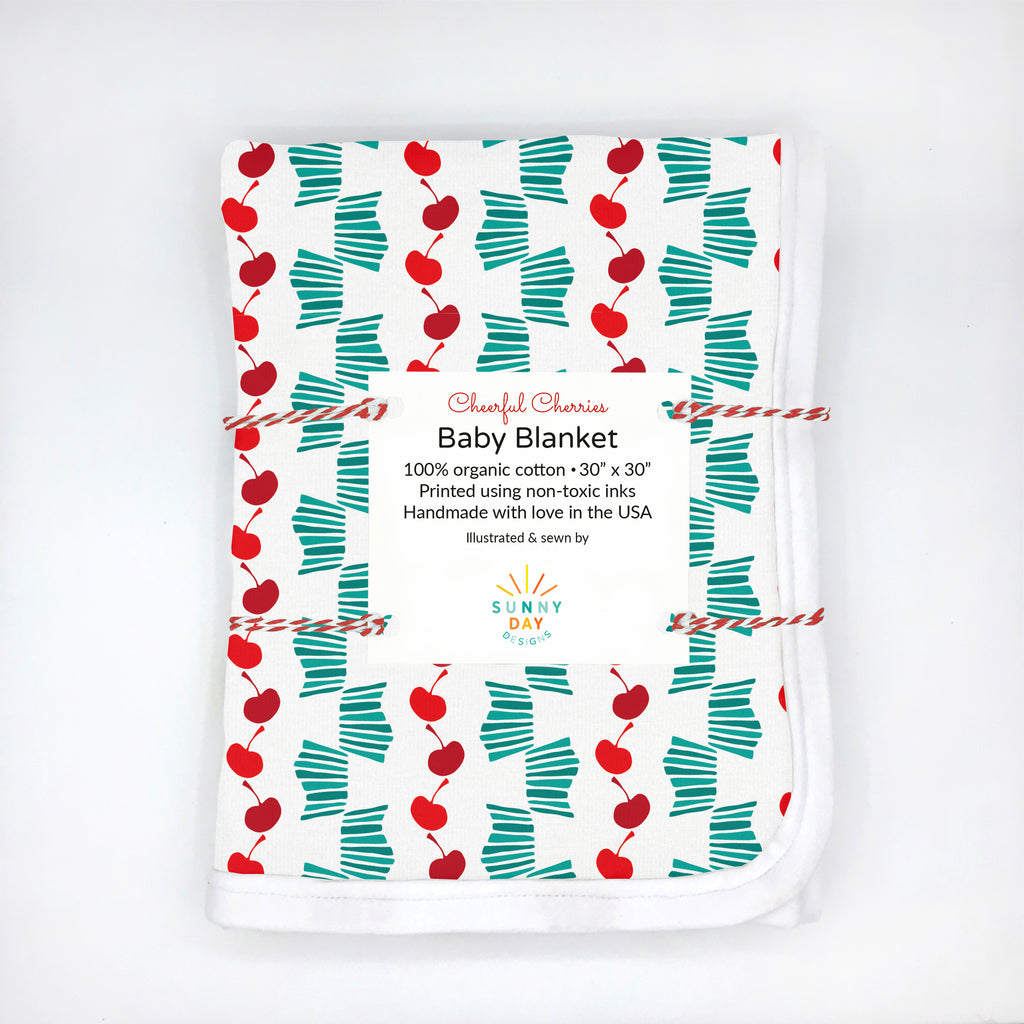 festive and fun cheerful cherries baby blanket with green and red print on white background