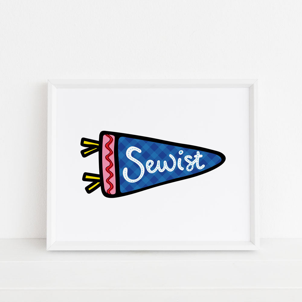 This sewing art print features a colorful illustrated pennant on a white background, which is emblazoned with the term "Sewist". Perfect for those who love to sew, this wall art makes great craft room or sewing room decor! Our "Sewing Pennant" 8x10 art print design by Sunny Day Designs is made in the USA and printed on watercolor paper.